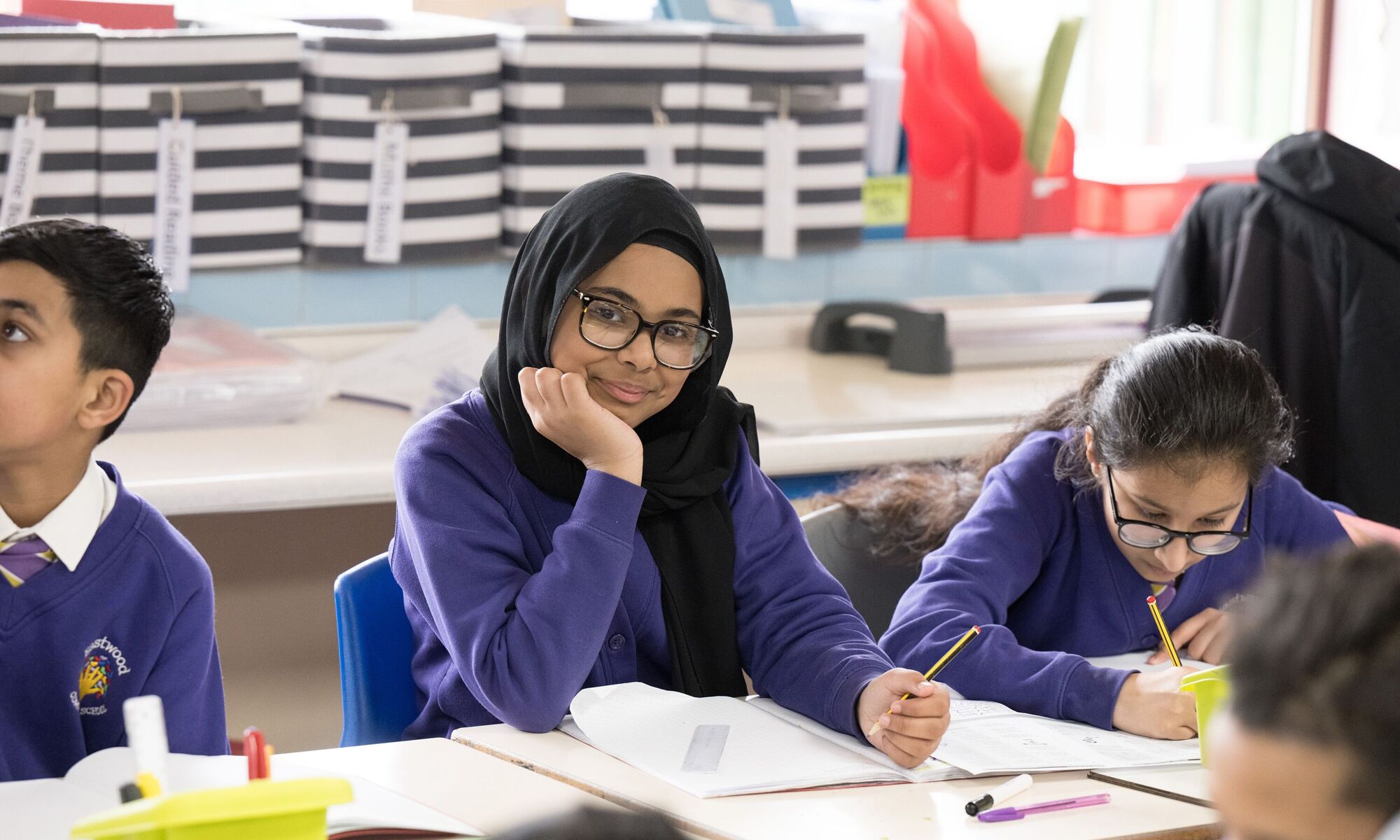 Eastwood Community School - Pupil smiling in class resting arm on table