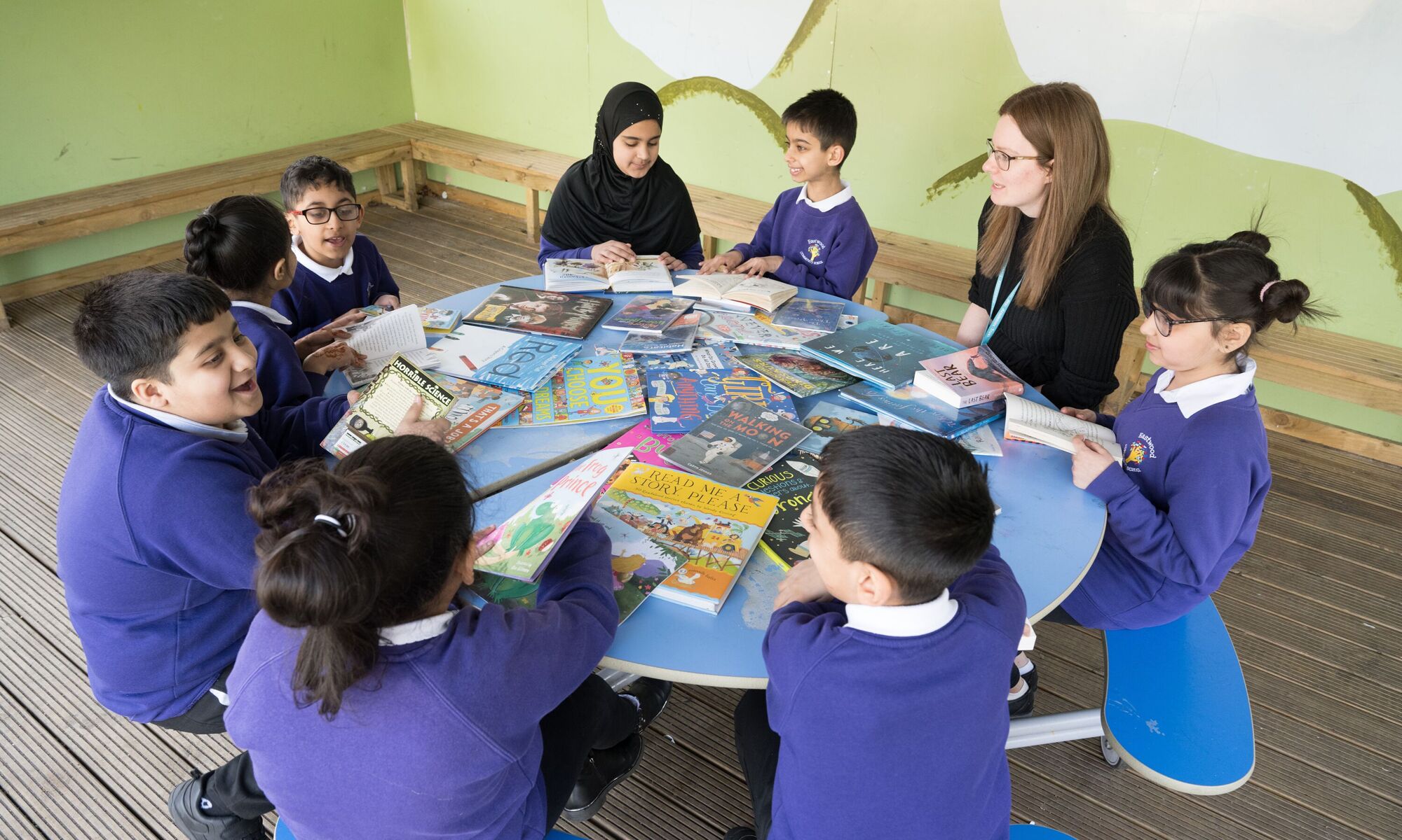 Eastwood Community School - Teacher and pupils sat around a table learning to read
