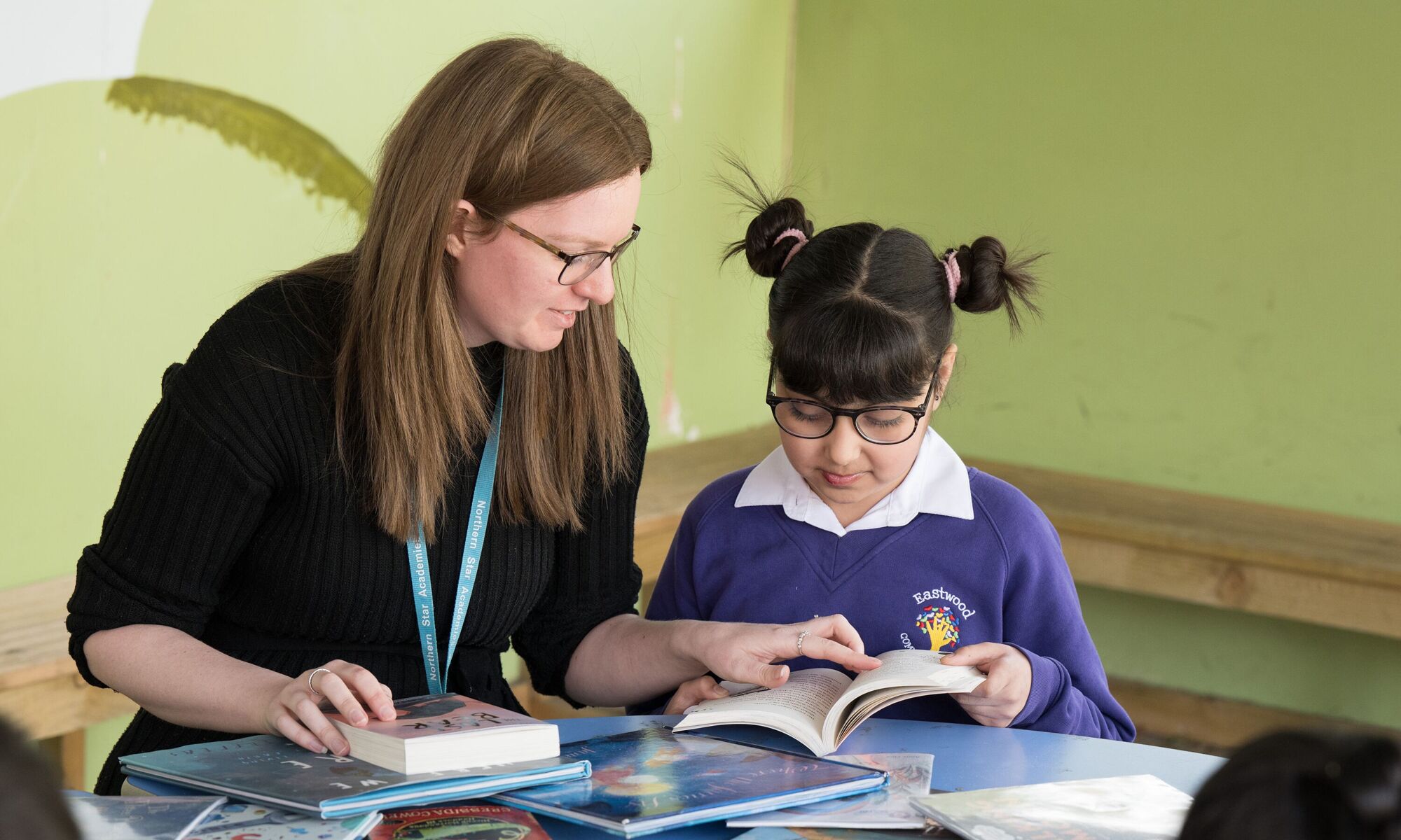 Eastwood Community School - Teacher and pupil reading together at a table